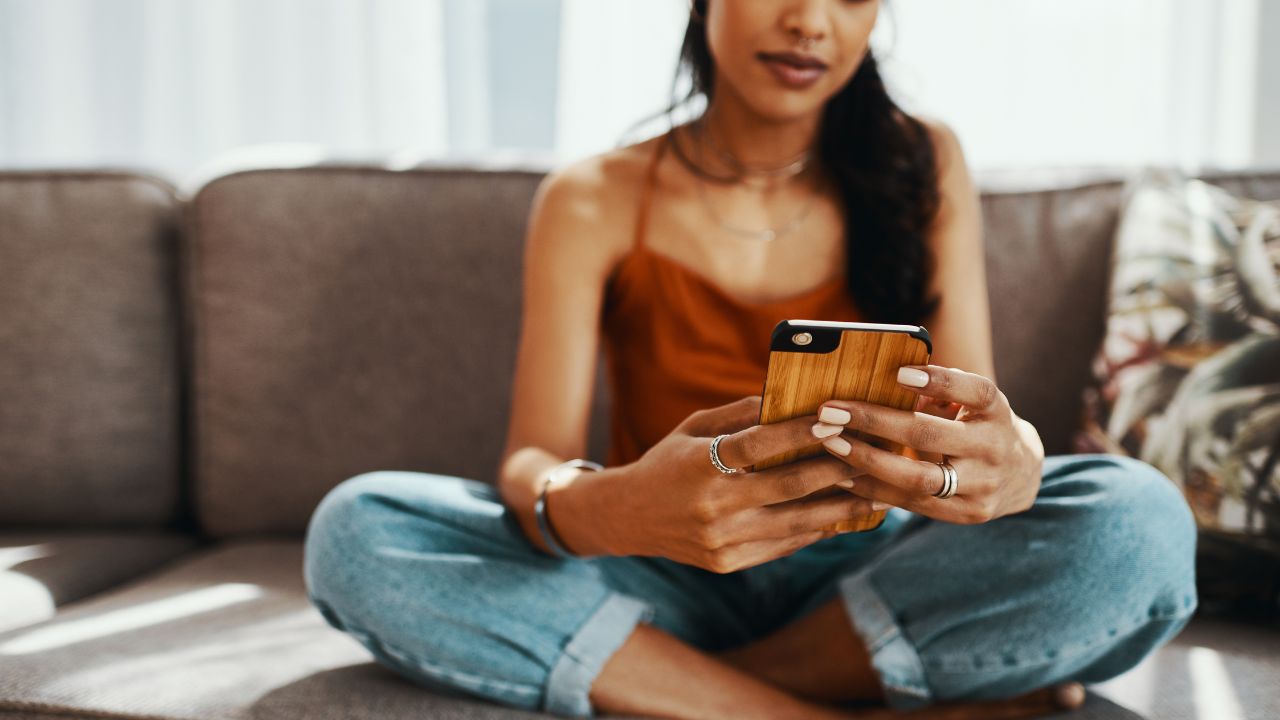 Une femme assise sur un canapé en train de consulter un site de rencontre