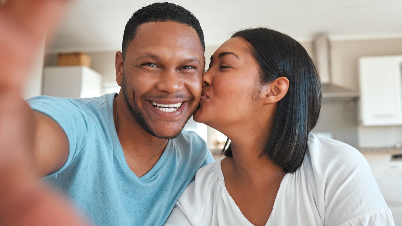 Un couple noir qui se fait un bisou sur la joue suite à leur rencontre faite depuis le site de rencontre 97tibo