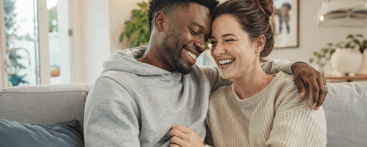 Couple mixte souriant qui partage un moment complice à la maison