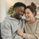 Couple mixte souriant qui partage un moment complice à la maison
